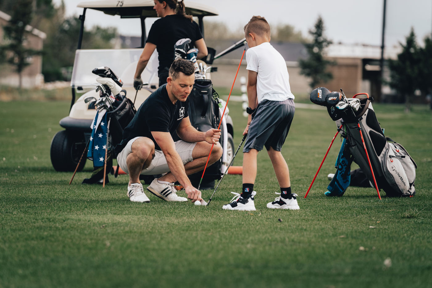 A Tee Box employee working with a group of kids on a golf course in Houston, TX.